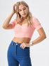 Woman wearing a peach ruched square neck puff sleeve crop top