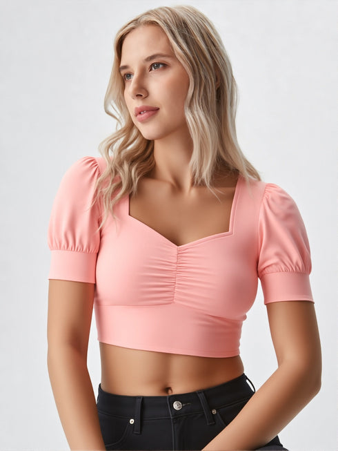 Woman wearing a peach ruched square neck puff sleeve crop top