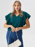 Woman wearing a green ruffle sleeve v-neck top paired with denim jeans