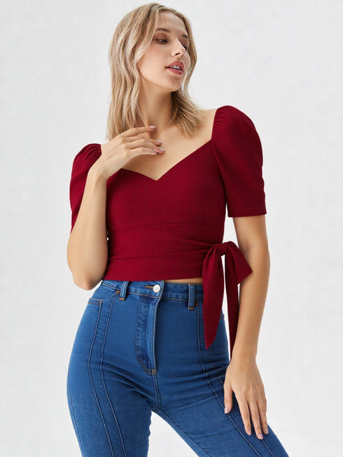 Woman wearing a wine red puff sleeve wrap top with tie waist