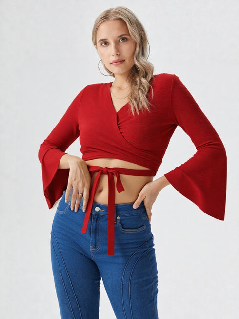 Woman wearing a red flared sleeve wrap crop top with tie detail