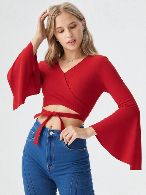 Woman wearing a red flared sleeve wrap crop top with tie detail