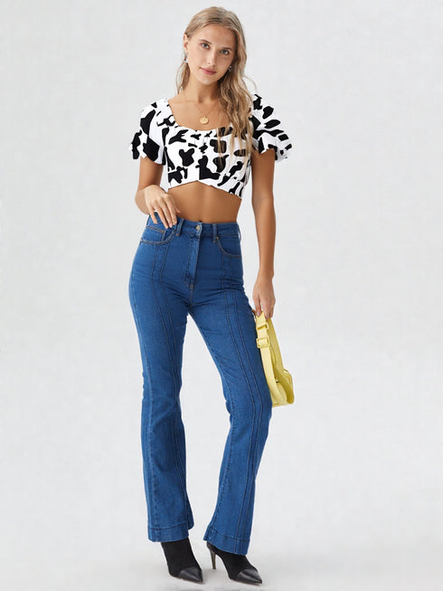 Woman wearing white cow print ruched puff sleeve crop top with puff sleeves and denim jeans