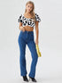 Woman wearing white cow print ruched puff sleeve crop top with puff sleeves and denim jeans