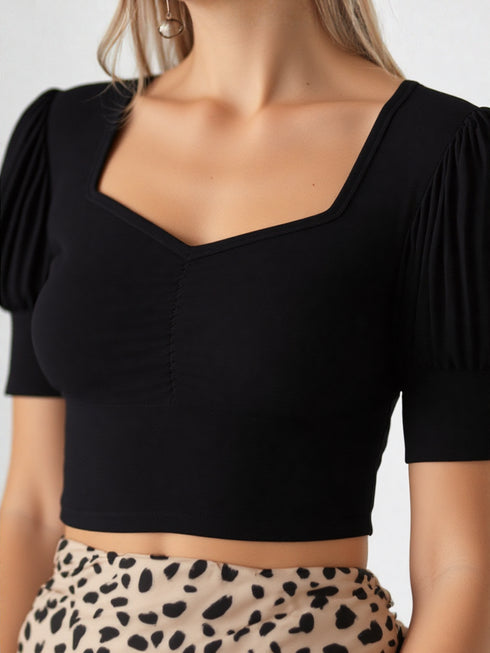 Close-up of woman wearing black sweetheart neck puff sleeve crop top with printed skirt