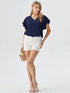 Woman wearing navy blue ruffle sleeve V-neck top with white shorts
