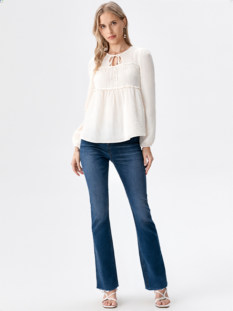 Close-up of woman wearing white ruffle detail tie neck blouse with long sleeves  