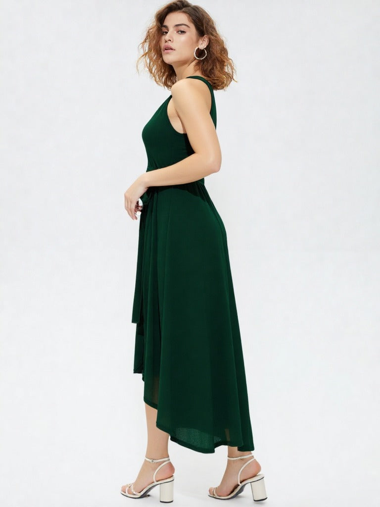 Woman wearing dark green halter neck asymmetrical maxi dress with tie waist belt and white heels  