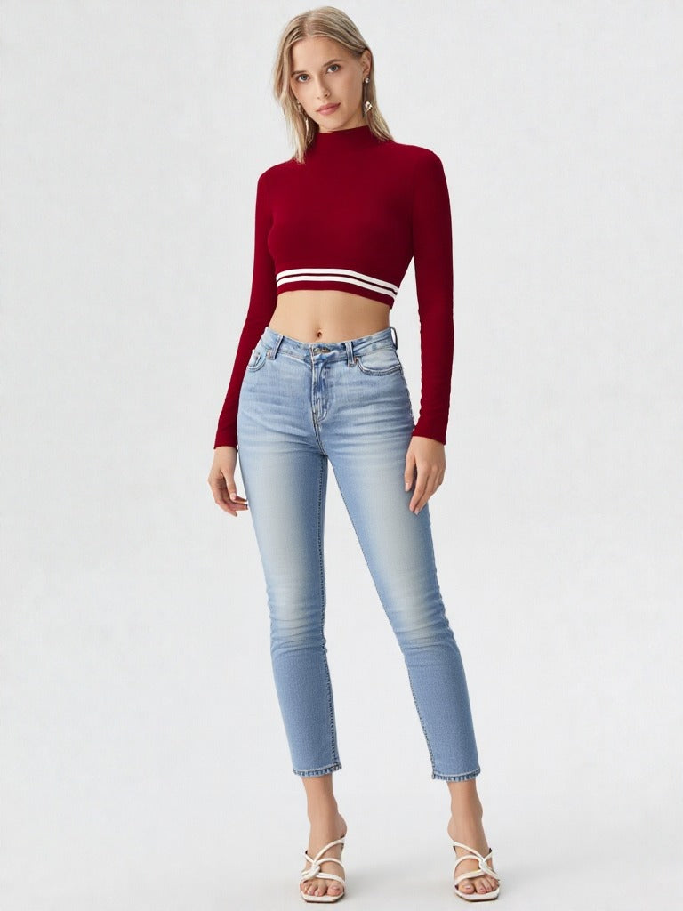 Woman wearing wine red mock neck long sleeve crop top with striped hem paired with denim shorts  