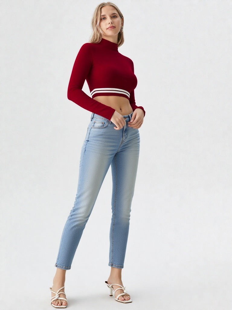 Woman wearing wine red mock neck long sleeve crop top with striped hem paired with denim shorts  